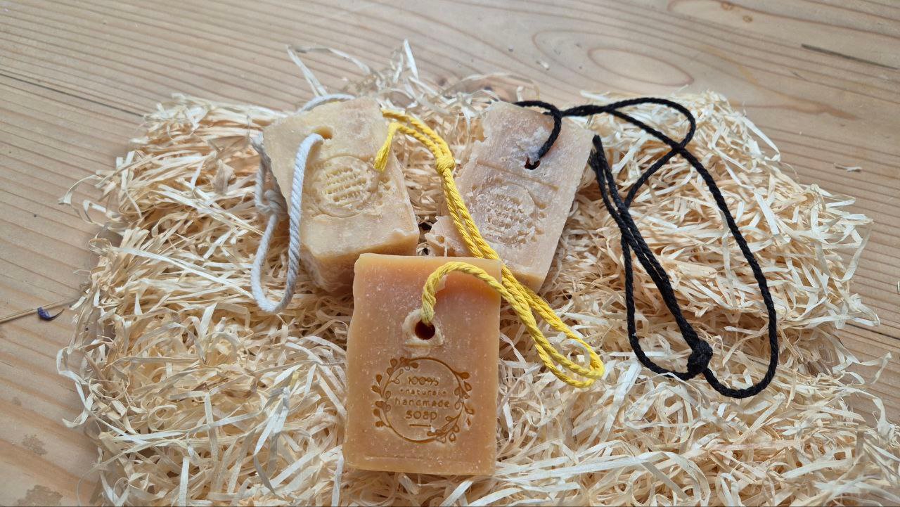 3 Stück Haarseife auf Stroh auf einer Holzunterlage
