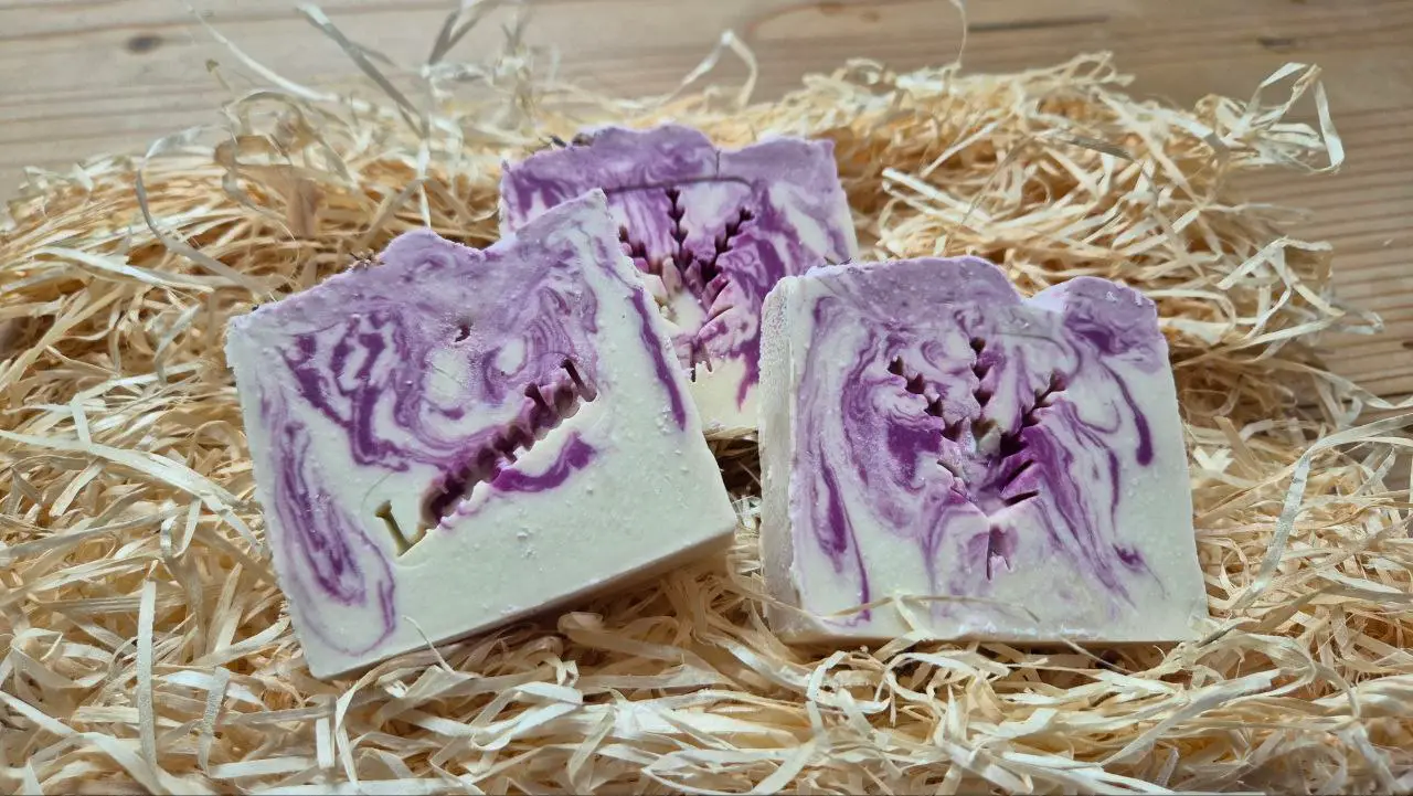 3 Stück Lavendelseife auf Stroh auf Holzunterlage