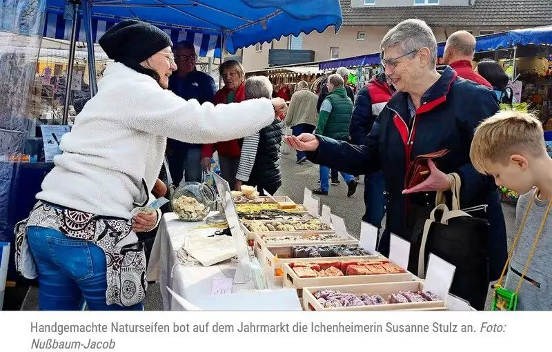 Susanne an Ihrem Marktstand, zeigt Besuchern eine Seife